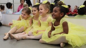 Smiling young ballerinas in yellow tutus