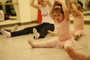 Young girl in pink ballet class stretching